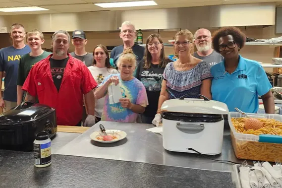 A group of UAW Local 2000 members gathers around the kitchen, preparing the meal that will serve as a fundraiser for local law enforcement.