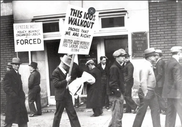 Striking autoworkers march on a picket line outside a building marked "The Chevrolet Motor Ohio Co."